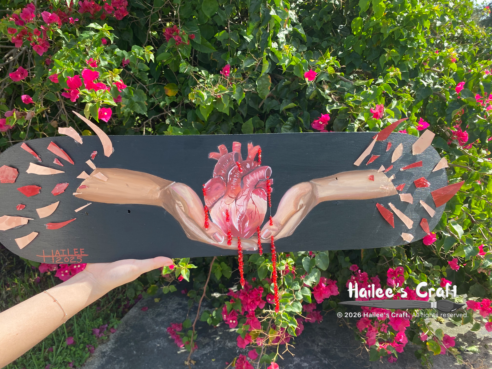 two hands painted on the baseplate of a skate board. the hands have real peices of glass attached to the arms. it looks as if the arms are bteaking into a million shards of glass. in the two hands is an anatomically correct heart. the heart is bleeding sparkly red gems.